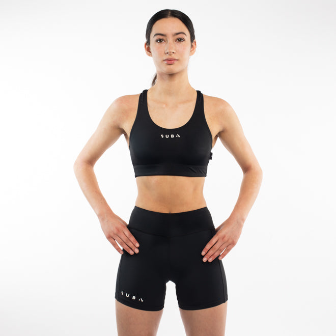 Woman wearing a black sports bra and shorts with 'SUB4' branding on a white background