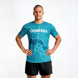 Man wearing a blue t-shirt with 'Canberra' printed on it against a white background