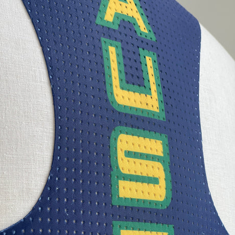 Close-up of a sports running singlet with blue and white design and green and yellow text.