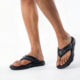 Black sandals worn by a person on a white background